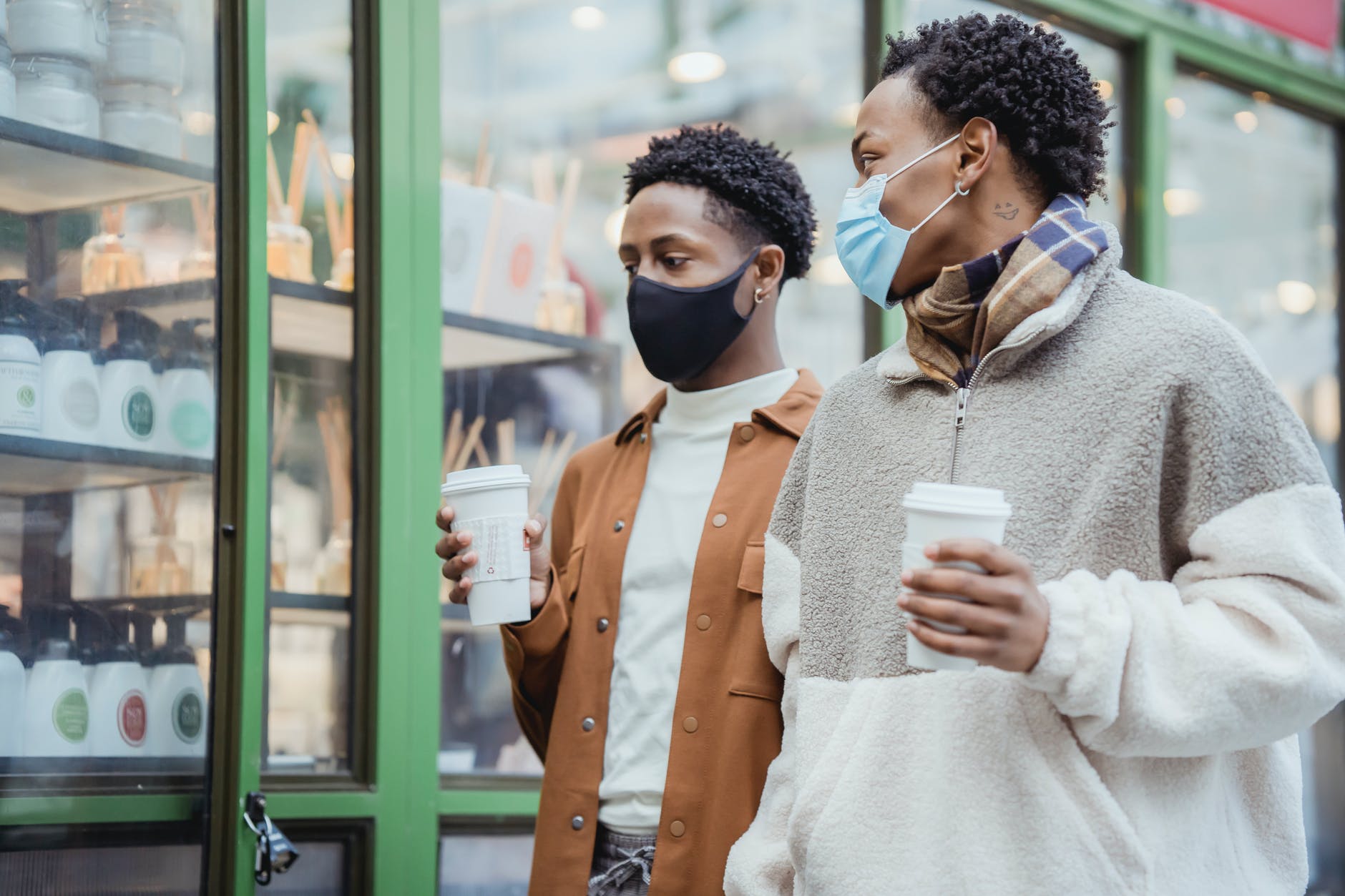 trendy black men walking on city street with takeaway coffee in hands